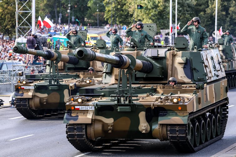 Two howitzers parade down a street