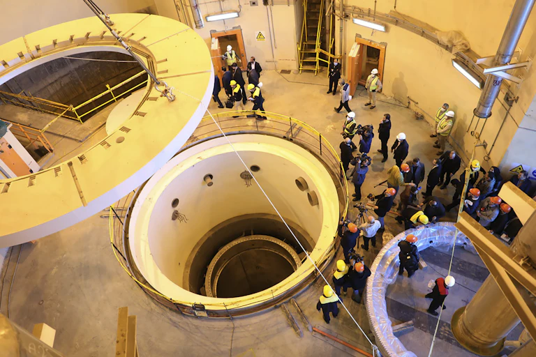 People gathered around a deep chamber in a nuclear reactor facility