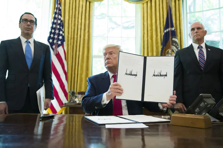 Donald Trump holding up an executive order.