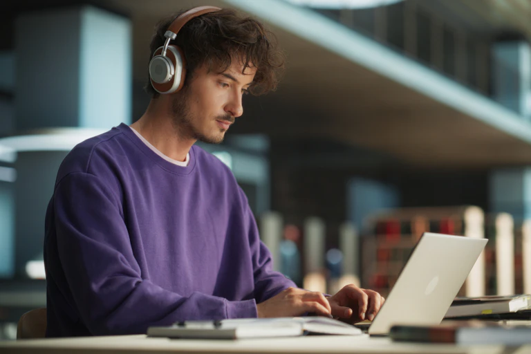 Man wears headphones while using a laptop computer