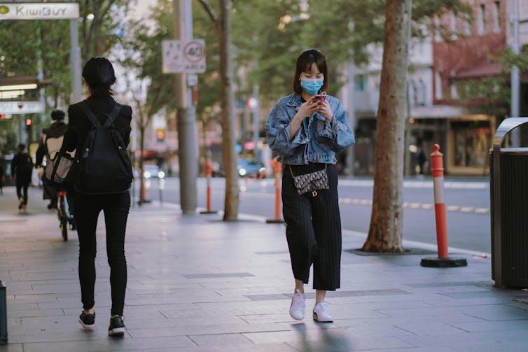 A woman wearing a mask walking in Sydney.