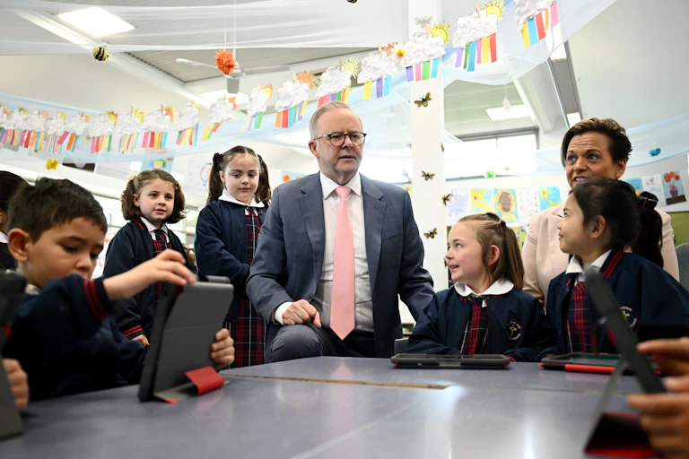 Prime Minister Anthony Albanese talks to young students in a classroom.