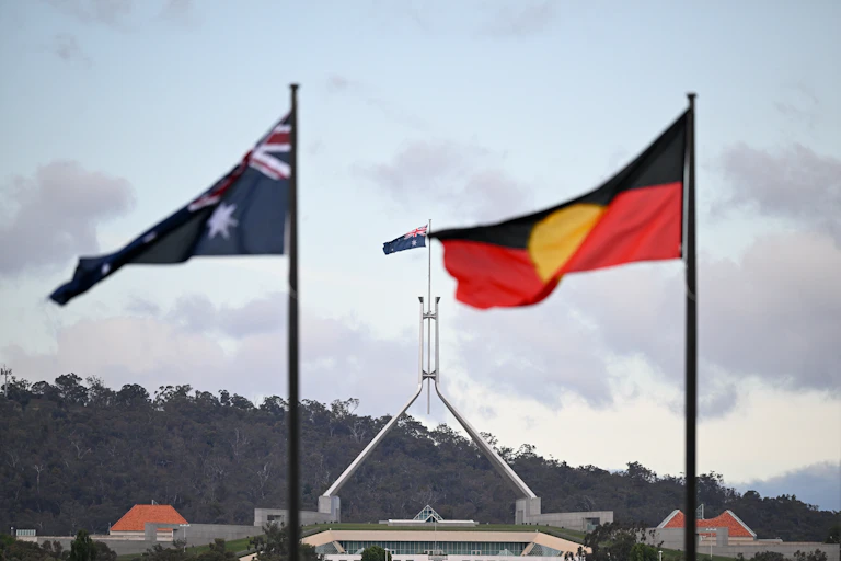 Australian and Aboriginal flags fly in front of parliament house