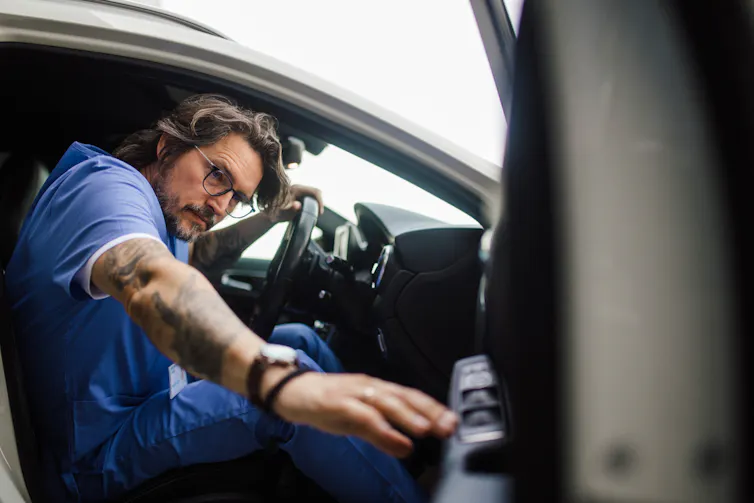 A medical worker closes the car door as he prepares to commute to work