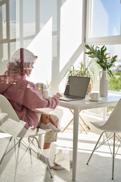 Girl seen through a window working on a laptop