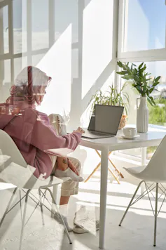 Girl seen through a window working on a laptop