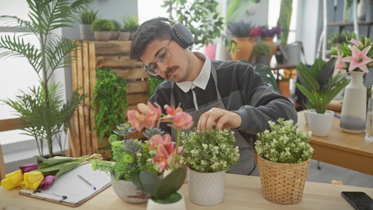 Man wearing headphones arranges flowers in a florist shop