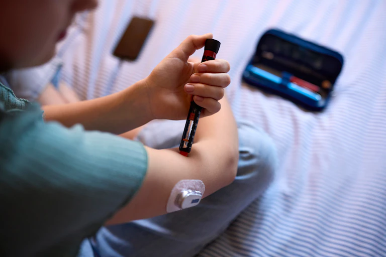 Close up of a girl given herself an insulin injection.