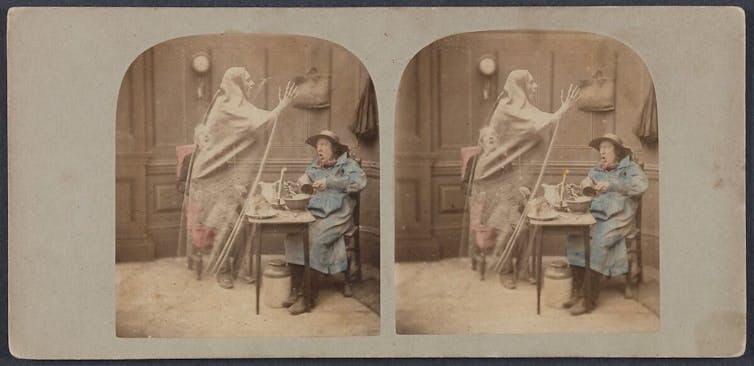 Stereoscope image of two men at a small table being surprised by a looming ghost.