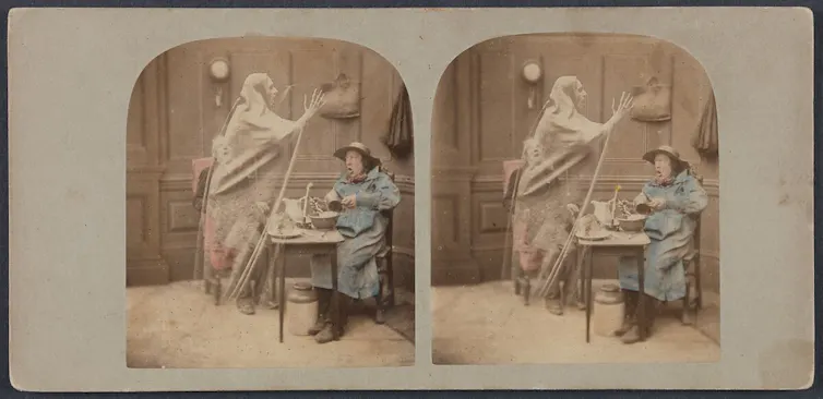 Stereoscope image of two men at a small table being surprised by a looming ghost.