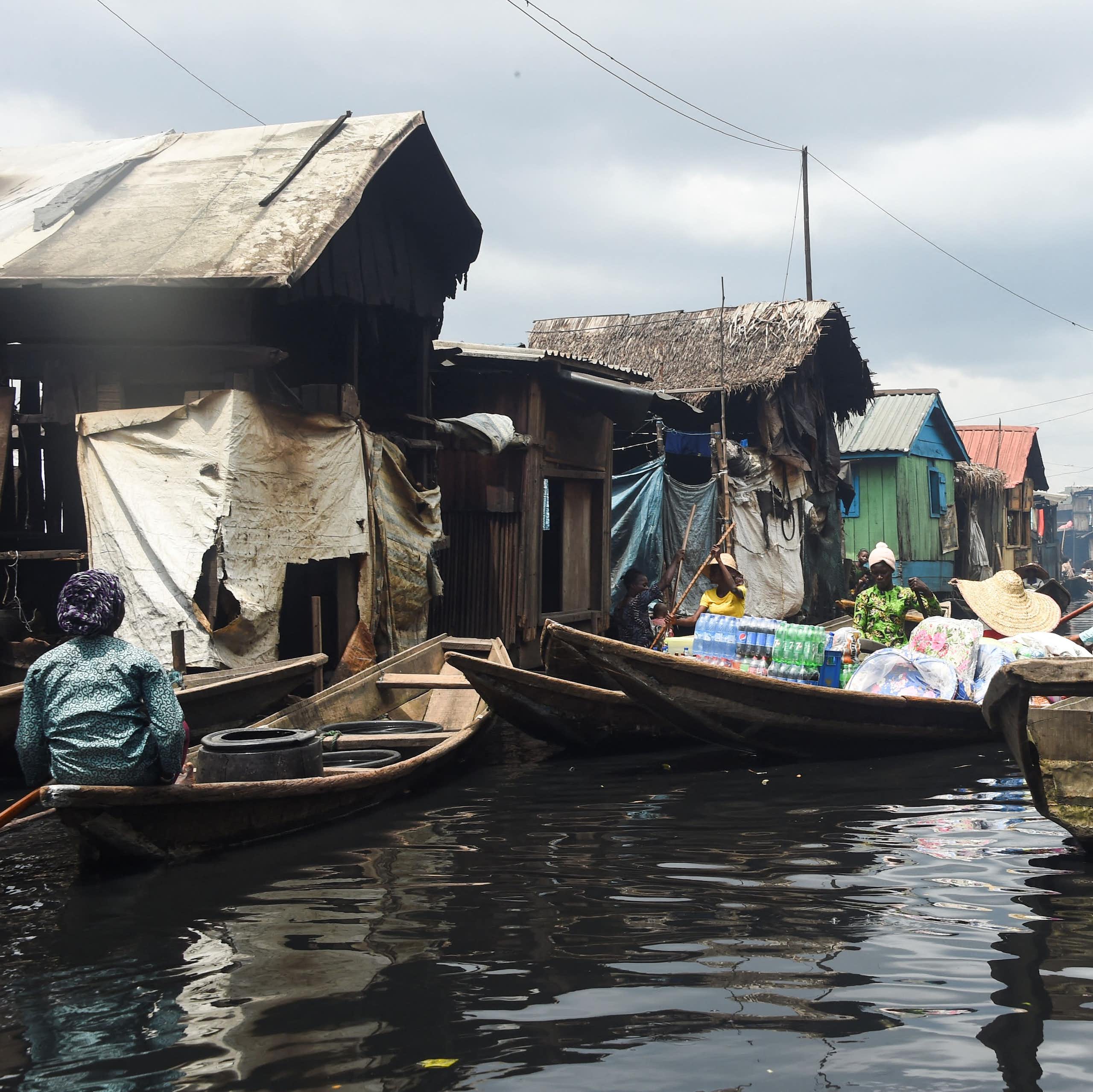 People on canoes amid wooden structures