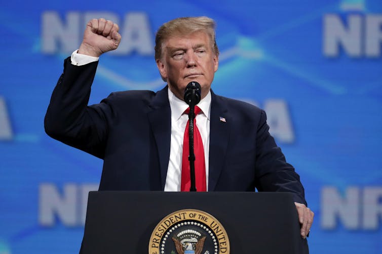 A man stands at a lectern with a raised fist.