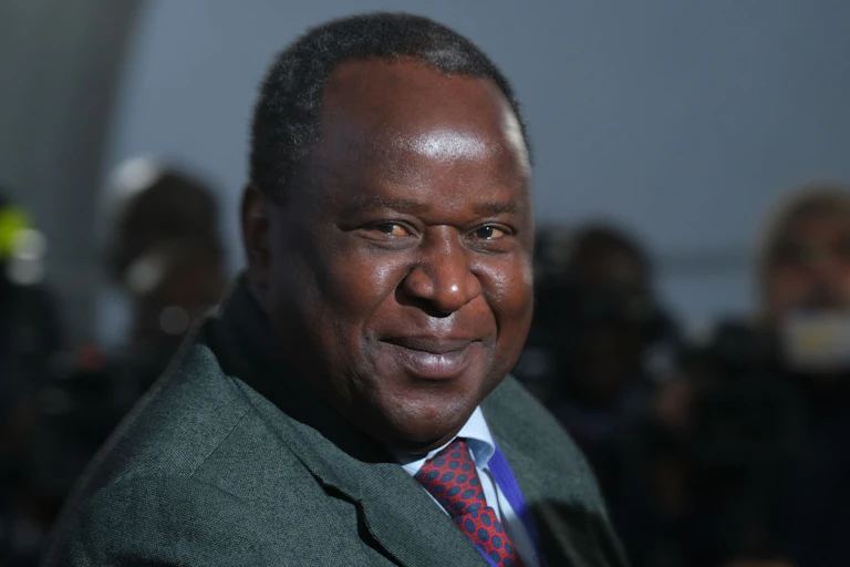 A man in a suit and tie smiles at the camera