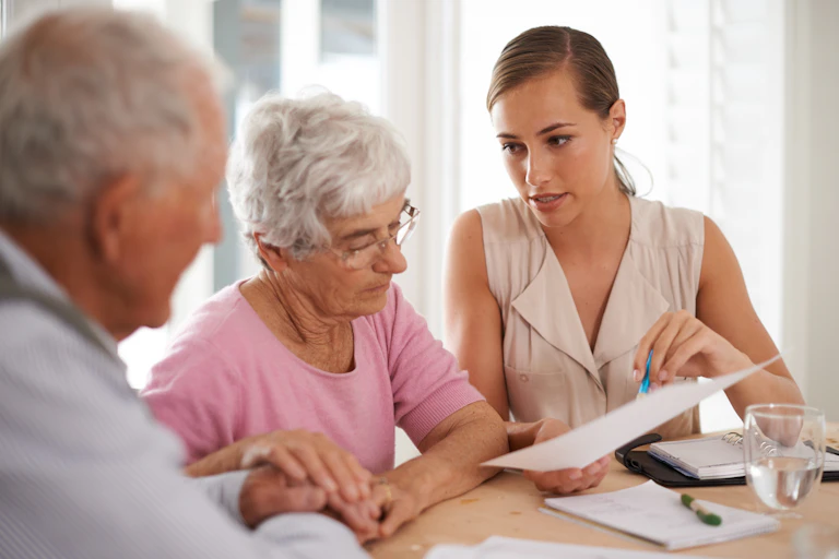 Elderly man and woman being shown a document by a younger woman