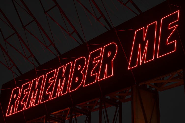 red neon lettering reads 'REMEMBER ME'