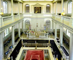 A narrow sanctuary with two floors of seating, painted white.