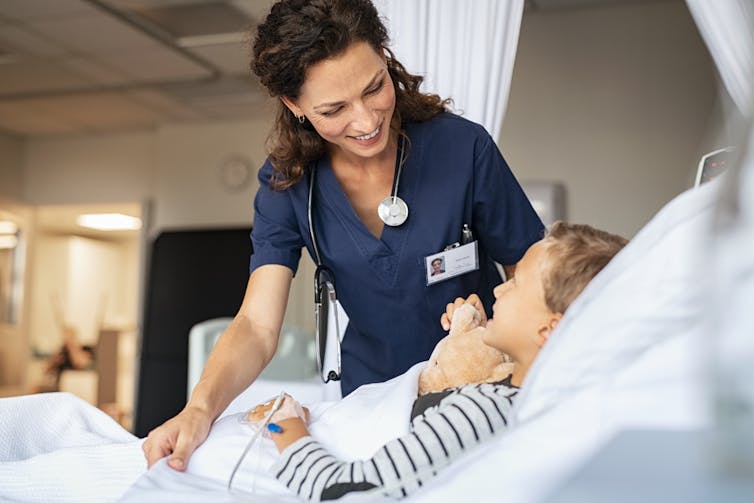 Woman tucking a sick child into bed