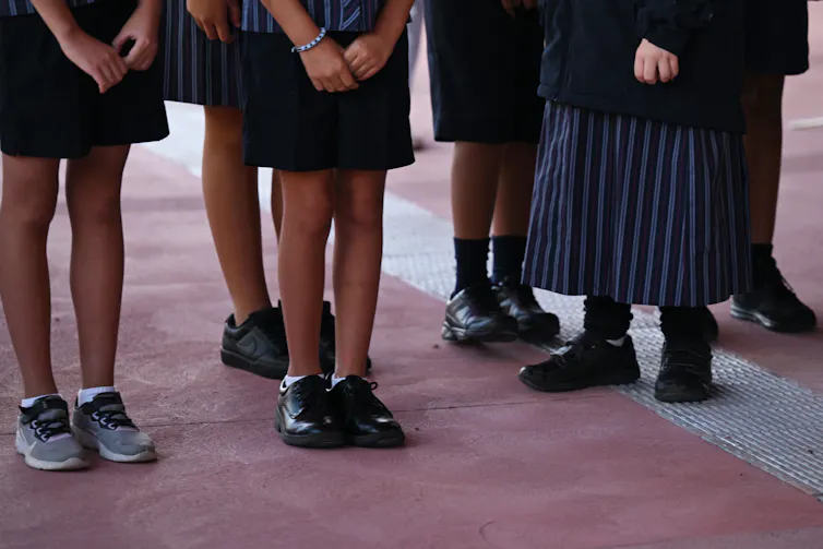 Primary students stand in the playground at school.