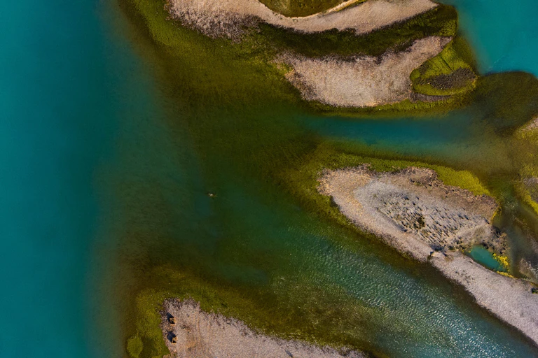 aerial shot of bright turquoise river water and stony islands