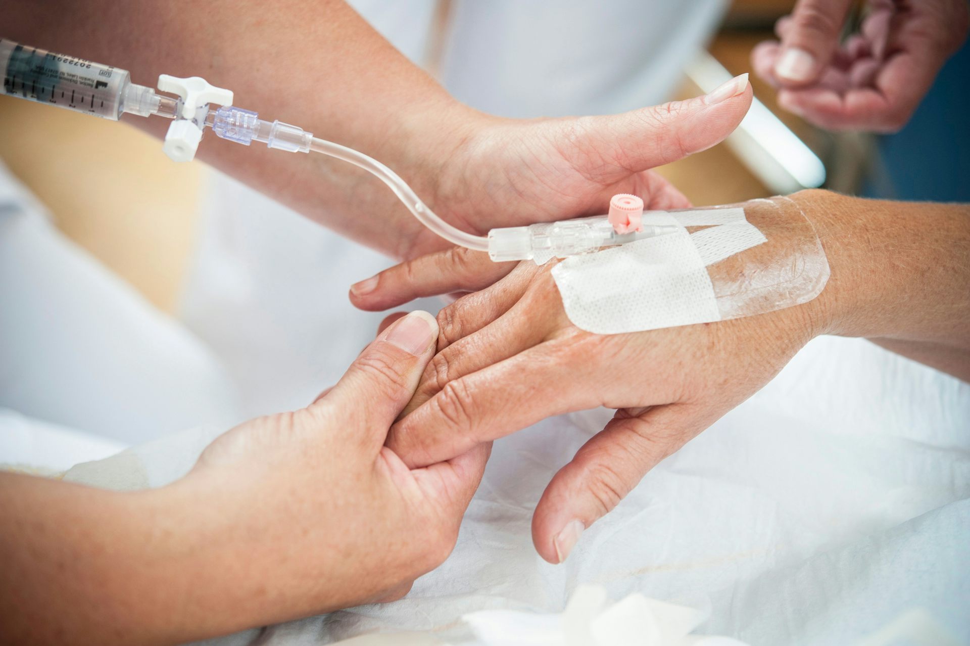A patient's hand with an IV line in the back.