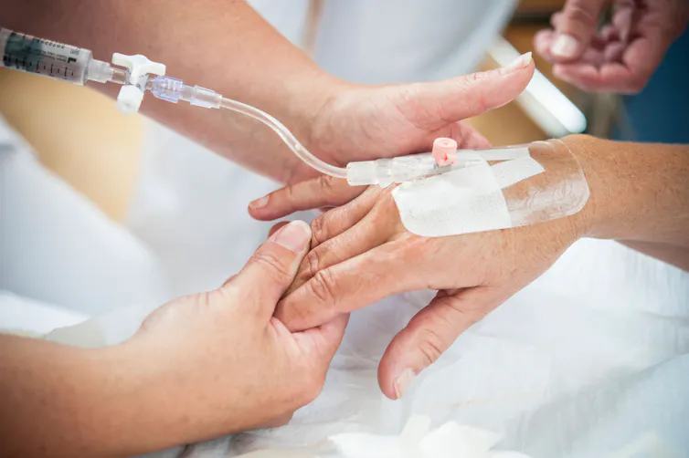 A patient's hand with an IV line in the back.