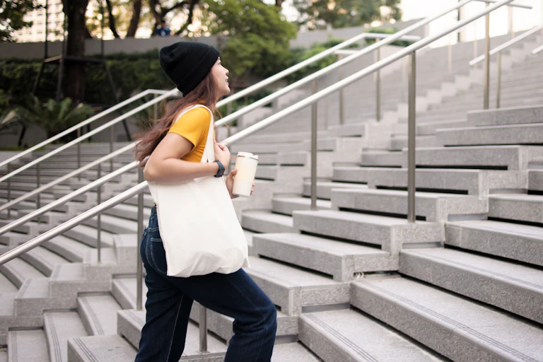 Woman with coffee cup walking up modern stairs