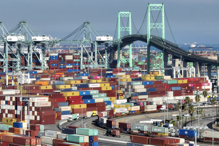 The Vincent Thomas Bridge, a 1,500-foot-long suspension bridge, is visible behind many dozen multicolored cargo containers.