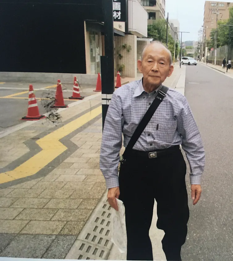 An elderly Japanese man walking down a street.