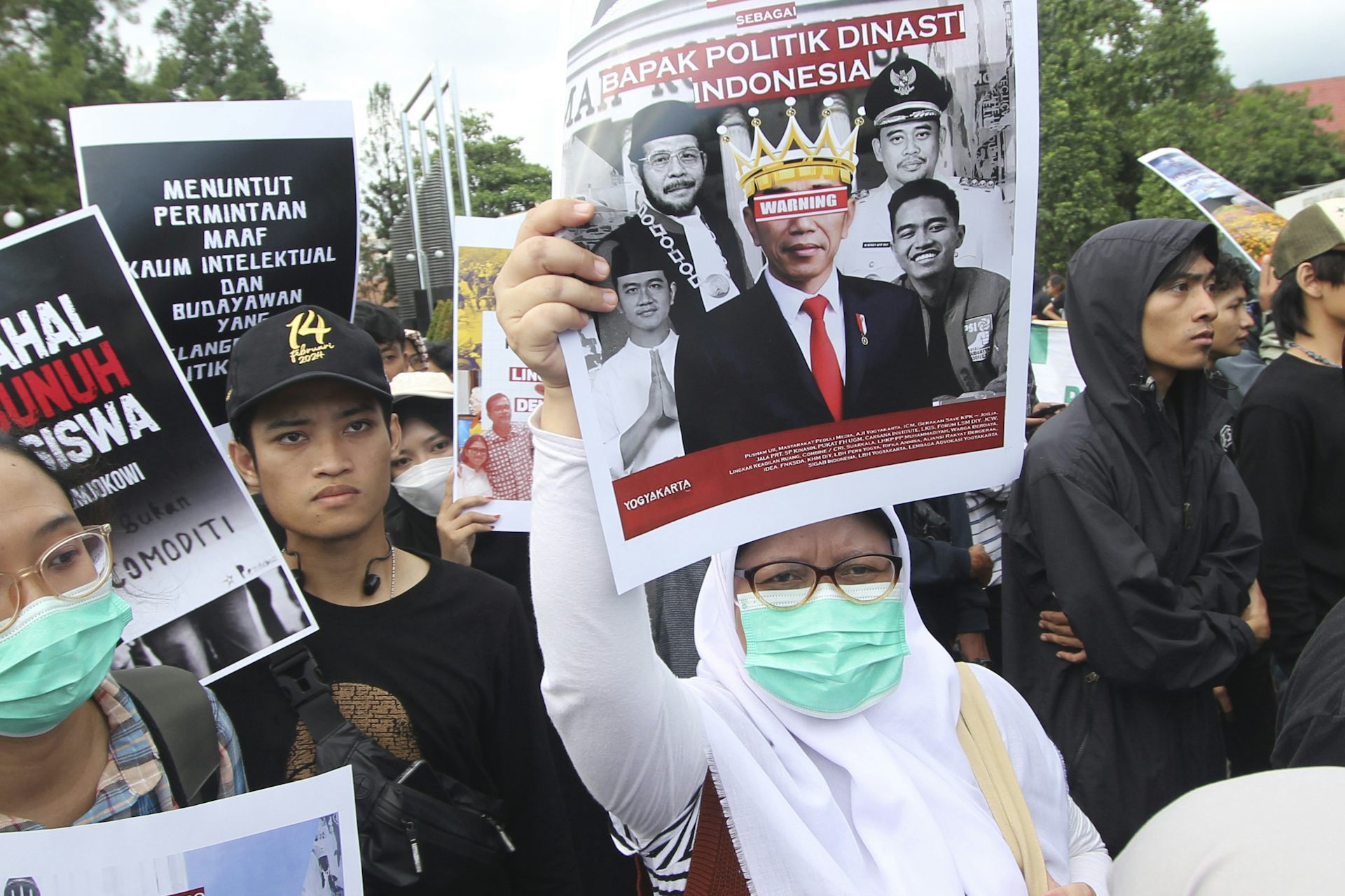 A protester holds up a poster with a defaced image of Joko Widodo.