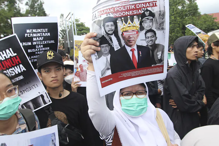 A protester holds up a poster with a defaced image of Joko Widodo.