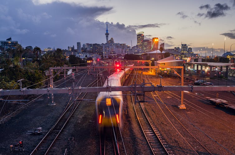 Railway crossing in Auckland with city in background.