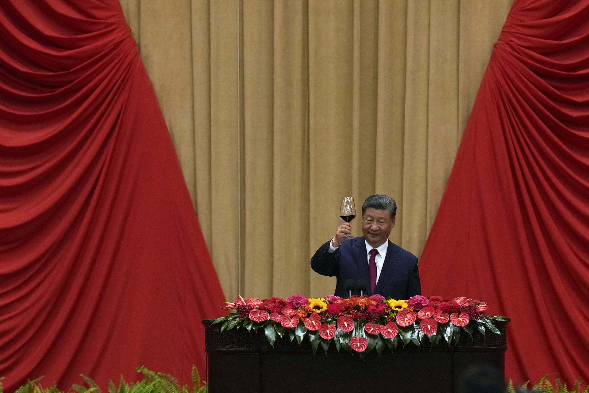 Chinese President Xi Jinping holds a glass of wine and makes a toast on stage after delivering his speech at a dinner