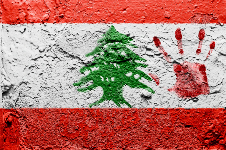 The Lebanese flag painted on a wall with bloody palmprint over it.