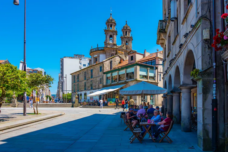A Mediterranean square with people beneath parasols.