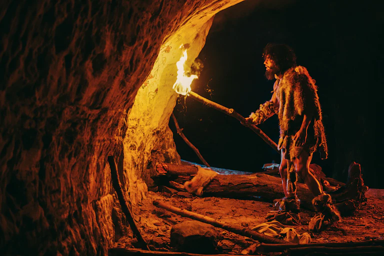 Homem em caverna segurando fogo contra pinturas
