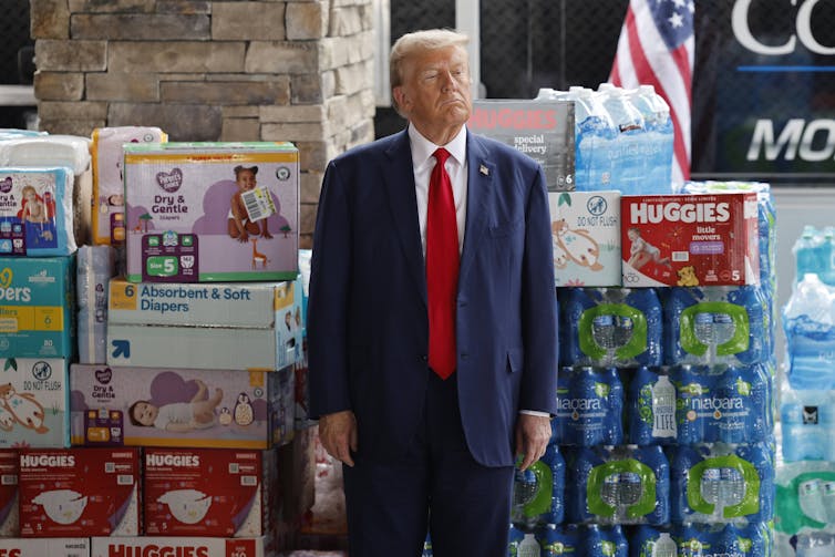 Donald Trump stood in front of nappies and water bottles