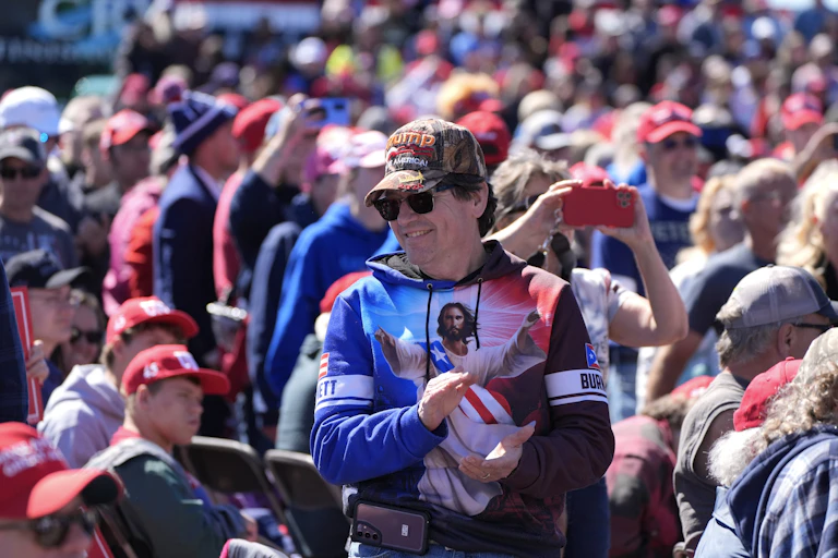 A man wearing a shirt depicting Jesus in the colors of the U.S. flag attends a political rally.