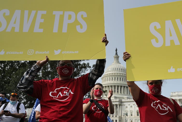 Demonstrators hold signs reading 'Save TPS' in front of the Capitol