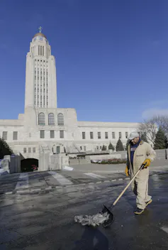 A government building, with a man sweeping up outside
