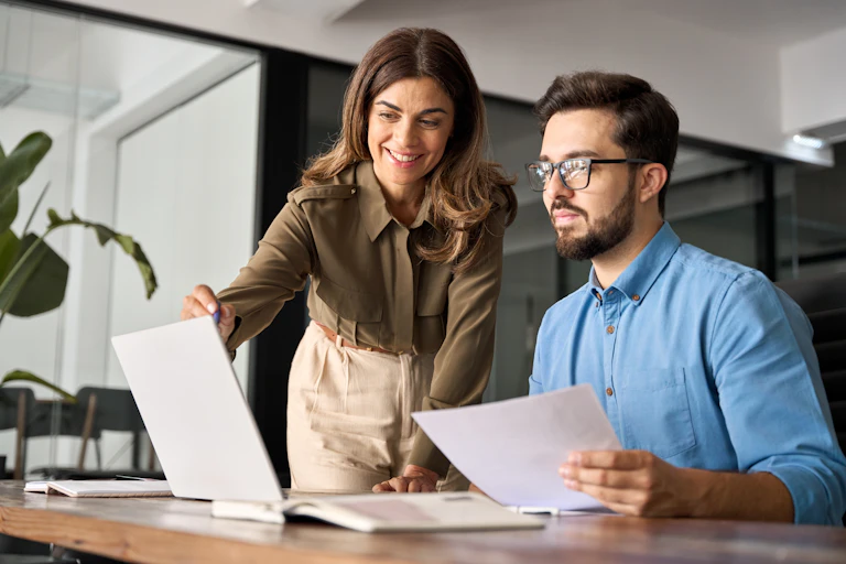 une femme et un homme dans un bureau devant un écran d'ordinateur portable