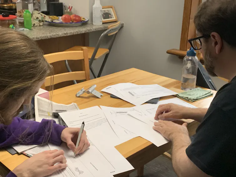 Two people sit at a kitchen table filling out their ballot.