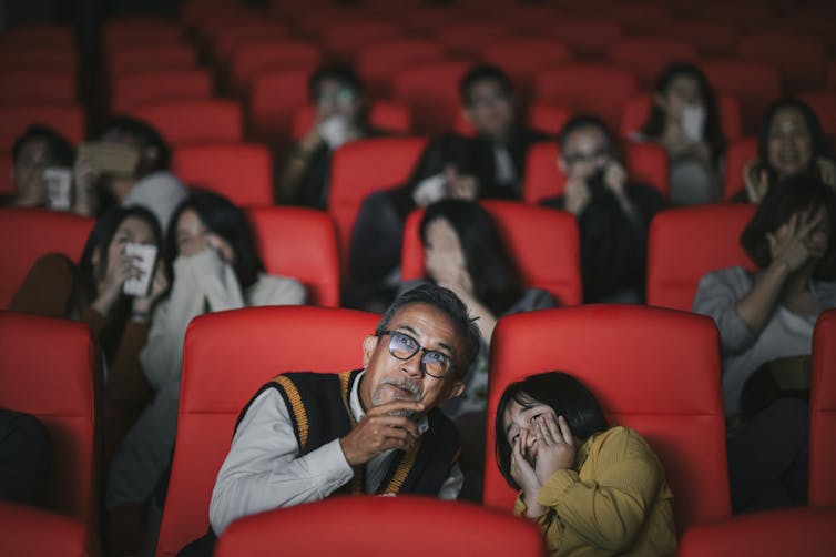man and girl lean together in movie theater