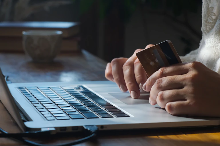 Person uses laptop holding a bank card