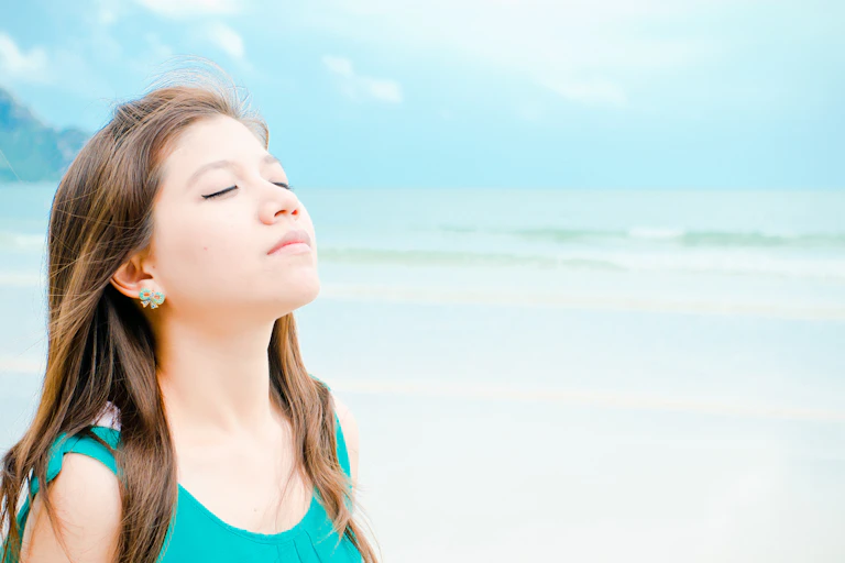 woman eyes closed smelling, sea in background