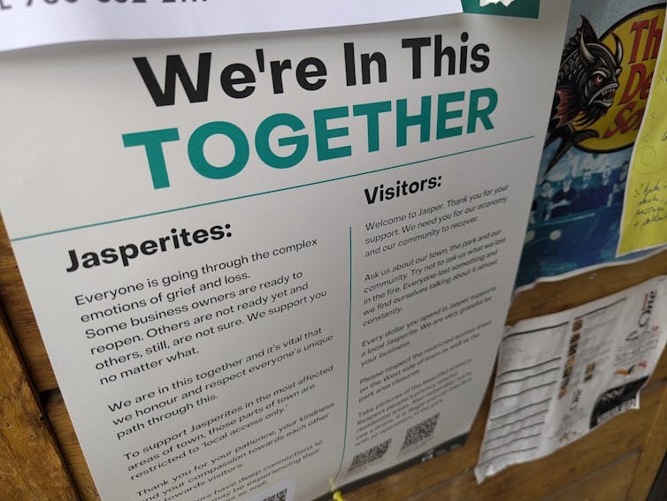 a sign with a large headline in black and green reading WE'RE IN THIS TOGETHER and one subhead that reads JASPERITES and a second that reads VISITORS