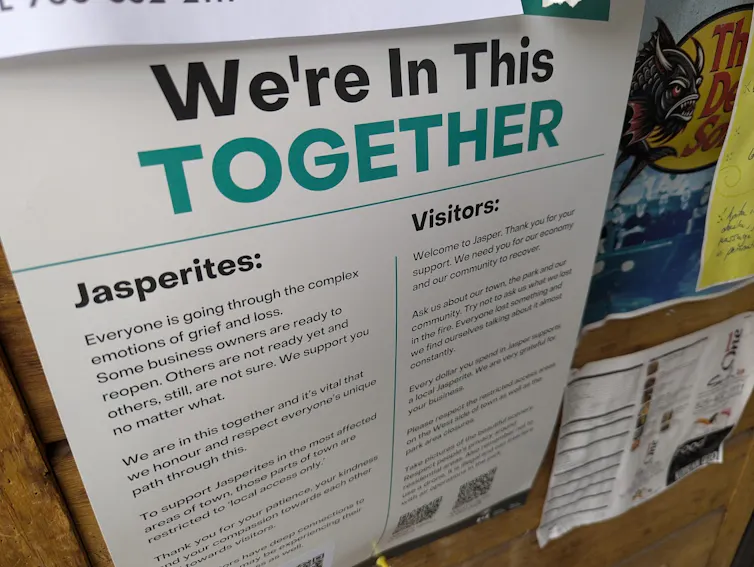 a sign with a large headline in black and green reading WE'RE IN THIS TOGETHER and one subhead that reads JASPERITES and a second that reads VISITORS