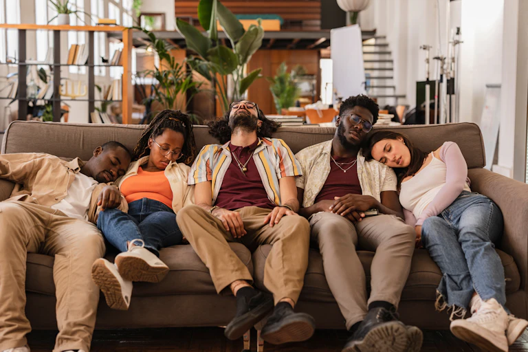 A group of students lay on a couch tired and hungover.