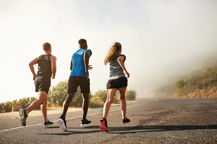 Three people go for a run on a road.