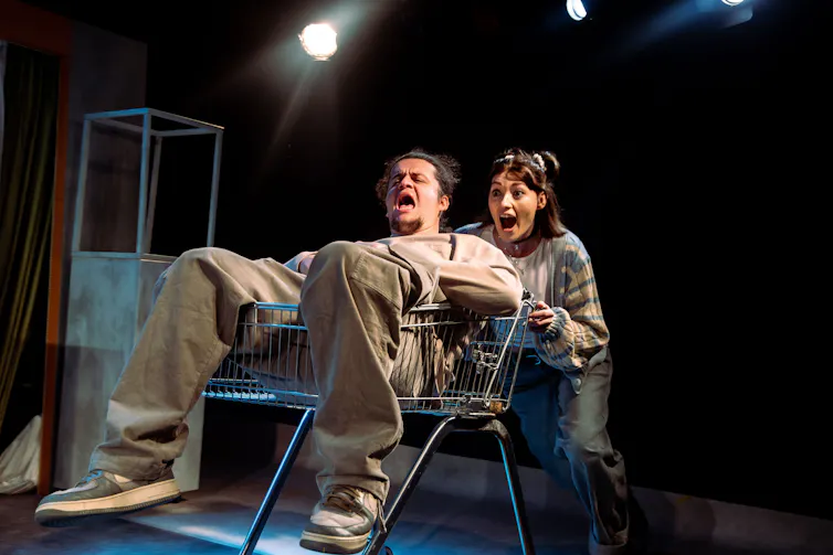 A boy and a girl playing around with a shopping trolley