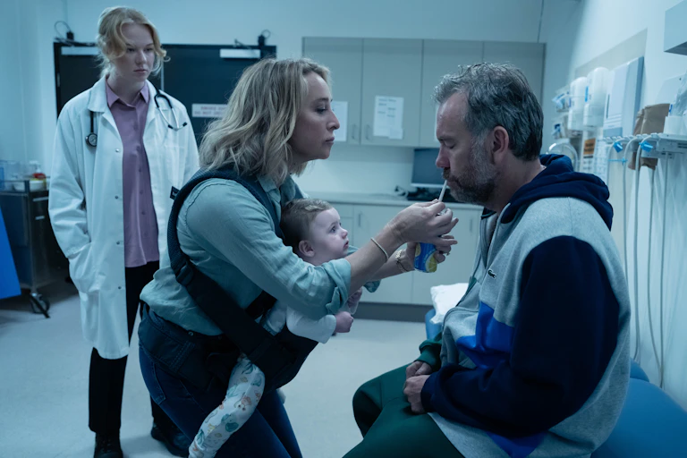 A scene from a drama shows a man sipping from a juice box on a doctor's chair.